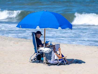 TOPSHOT - US President Joe Biden (L) and US First Lady Jill Biden sit under an umbrella in Rehoboth Beach, Delaware, on July 30, 2023. (Photo by Jim WATSON / AFP) (Photo by JIM WATSON/AFP via Getty Images)