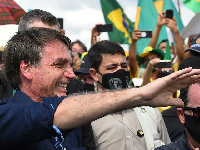 Brazil's President Jair Bolsonaro greets supporters upon arrival at Planalto Palace in Brasilia, on May 24, 2020, amid the COVID-19 coronavirus pandemic. Despite positive signs elsewhere, the disease continued its surge in large parts of South America, with the death toll in Brazil passing 22,000 and infections topping 347,000, the world's second-highest caseload. EVARISTO SA / AFP