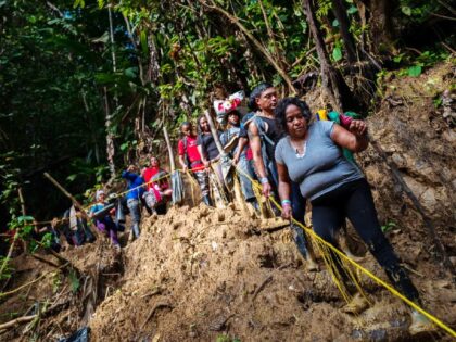 DARIEN GAP, COLOMBIA - NOVEMBER 20: Haitian migrants climb down a muddy hillside trail in the wild and dangerous jungle on November 20, 2022 in Darién Gap, Colombia. Tens of thousands of migrants from around the world make their journey to the Southern U.S border through South America every year, …