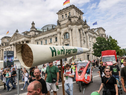 BERLIN, GERMANY - AUGUST 12: Cannabis supporters march with a giant mock joint past the Reichstag building in the annual Hemp Parade on August 12, 2023 in Berlin, Germany. The German coalition government has agreed on a general framework for the legalization of cannabis and is hoping to enact legislation …