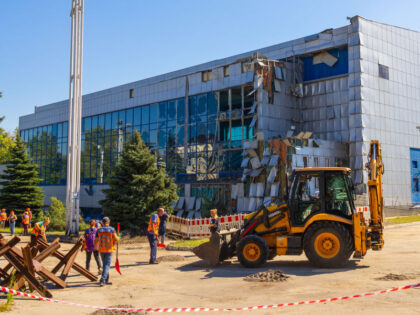 DNIPRO, UKRAINE - AUGUST 15: Workers with shovels and a backhoe clean up ground and debris near a sports complex damaged by one of the Russian missiles on August 15, 2023 in Dnipro, Ukraine. The building of the pool, which hosted international competitions, was damaged. (Photo by Informator.ua/Global Images Ukraine …